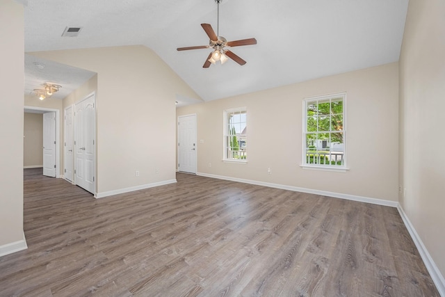 spare room with a ceiling fan, visible vents, wood finished floors, baseboards, and high vaulted ceiling