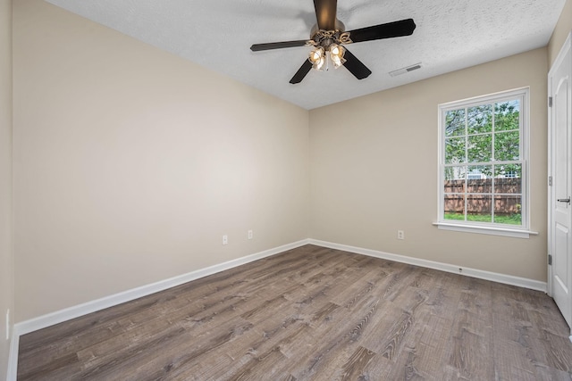 unfurnished room with a ceiling fan, baseboards, wood finished floors, and a textured ceiling