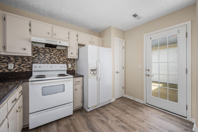 kitchen with visible vents, wood finished floors, white appliances, under cabinet range hood, and tasteful backsplash