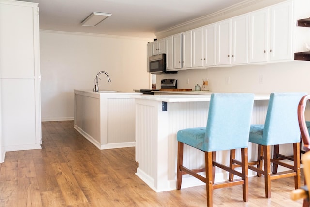 kitchen with electric range, crown molding, a center island with sink, a sink, and a peninsula