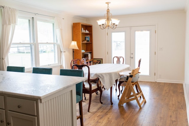 dining space featuring an inviting chandelier, crown molding, light wood-style floors, and a healthy amount of sunlight