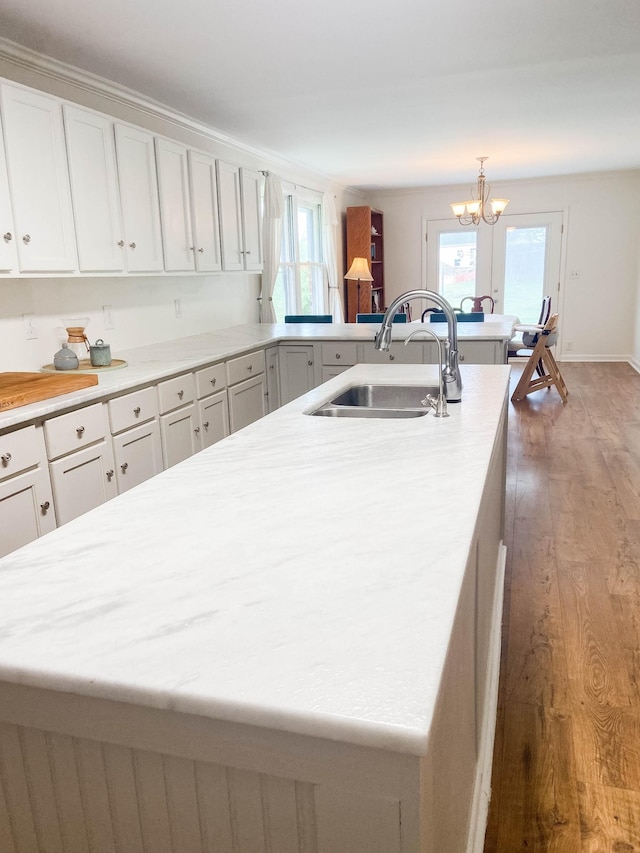 kitchen featuring a sink, wood finished floors, white cabinets, and light countertops