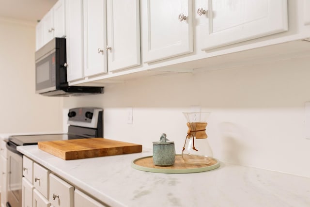 kitchen featuring light countertops, electric range oven, and white cabinetry