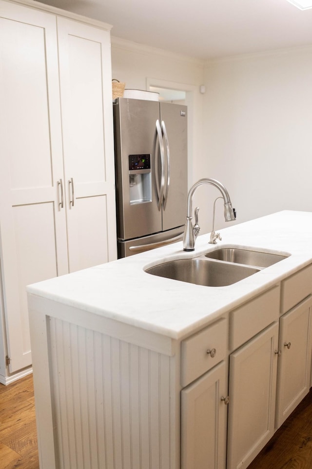 kitchen with light countertops, a sink, wood finished floors, and stainless steel fridge with ice dispenser
