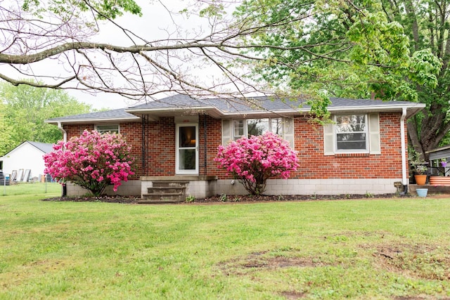 single story home with brick siding, a shingled roof, and a front yard