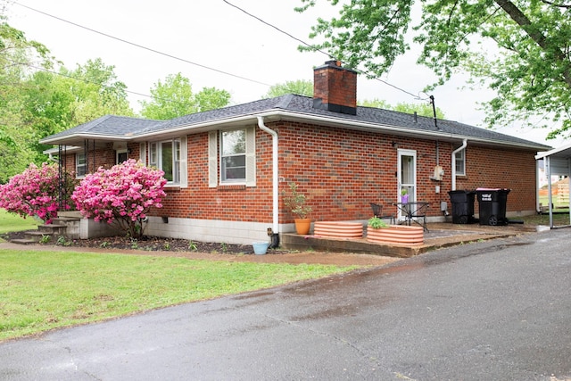 view of side of home with a chimney, a yard, and brick siding