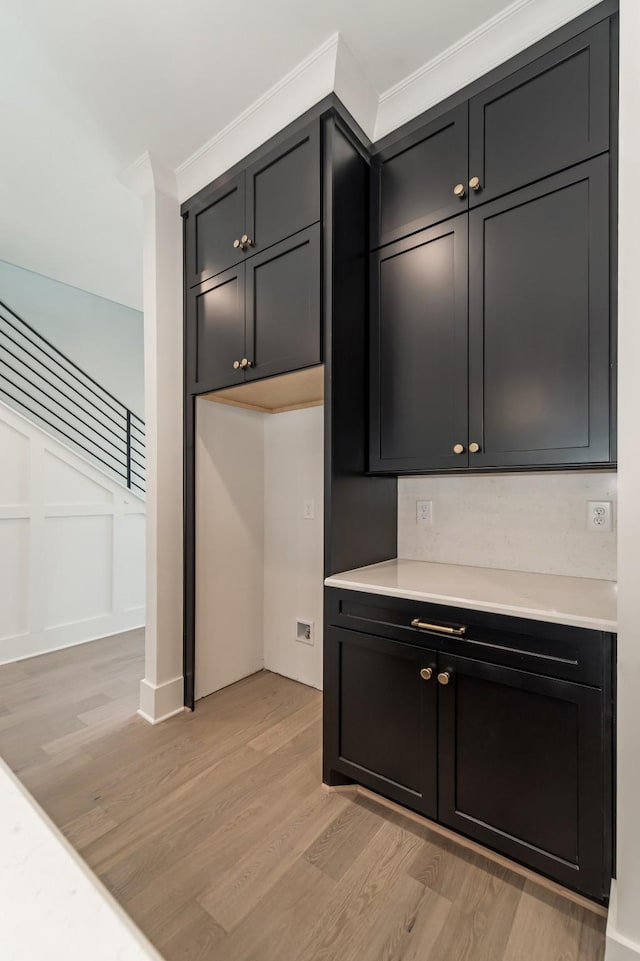 kitchen featuring light countertops, dark cabinets, and light wood finished floors