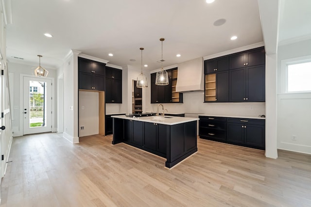kitchen featuring dark cabinetry, baseboards, custom exhaust hood, and light wood finished floors