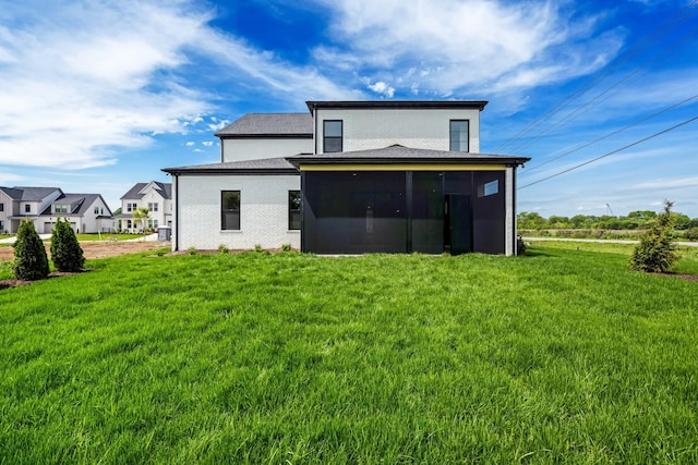 rear view of house featuring a lawn and a sunroom