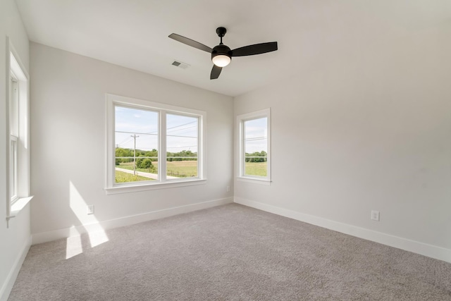 unfurnished room with visible vents, a ceiling fan, baseboards, and carpet floors