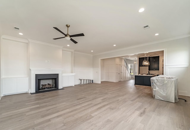 unfurnished living room featuring crown molding, ceiling fan, and a decorative wall