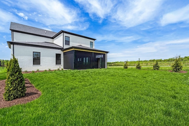 rear view of property with a lawn and a sunroom