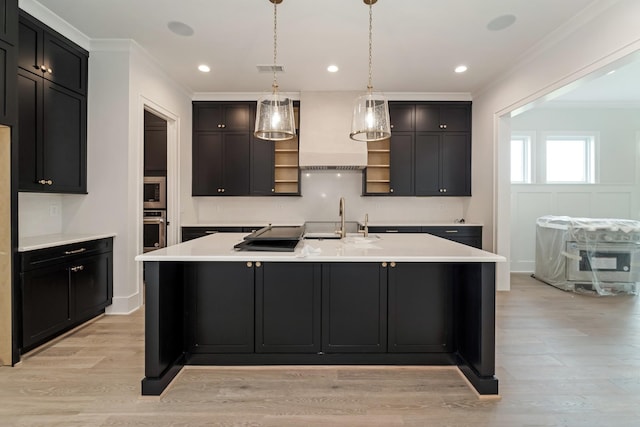 kitchen featuring crown molding, light countertops, appliances with stainless steel finishes, and a center island with sink