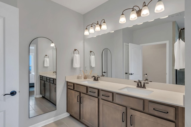 ensuite bathroom featuring double vanity, a sink, tile patterned floors, and visible vents