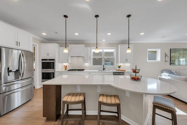 kitchen with crown molding, a sink, appliances with stainless steel finishes, and a healthy amount of sunlight