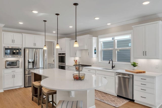 kitchen with tasteful backsplash, a sink, light wood finished floors, ornamental molding, and stainless steel appliances