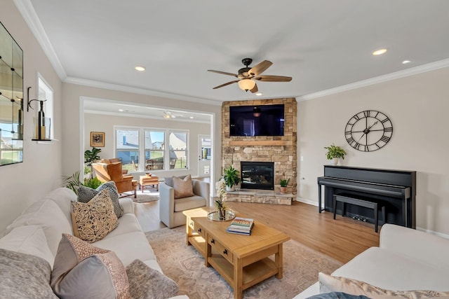 living area featuring crown molding, a fireplace, ceiling fan, recessed lighting, and light wood-style flooring