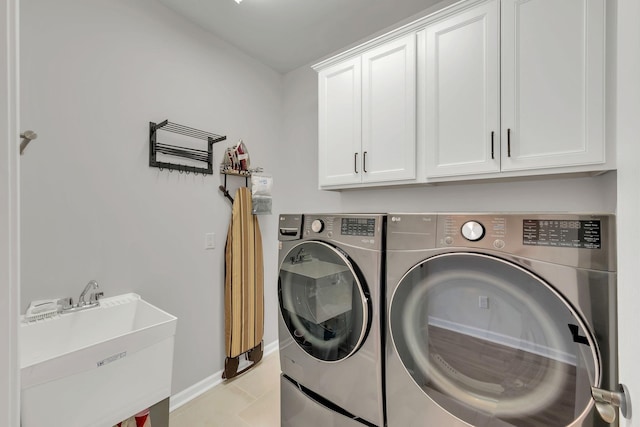 washroom with cabinet space, baseboards, a sink, and washer and clothes dryer