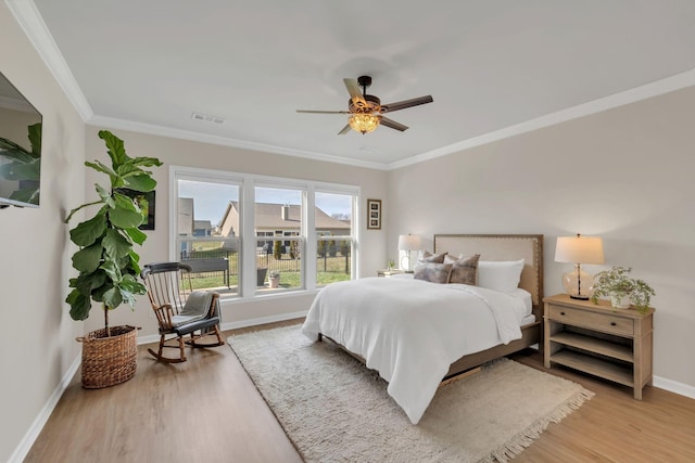 bedroom featuring visible vents, light wood-style flooring, crown molding, and baseboards