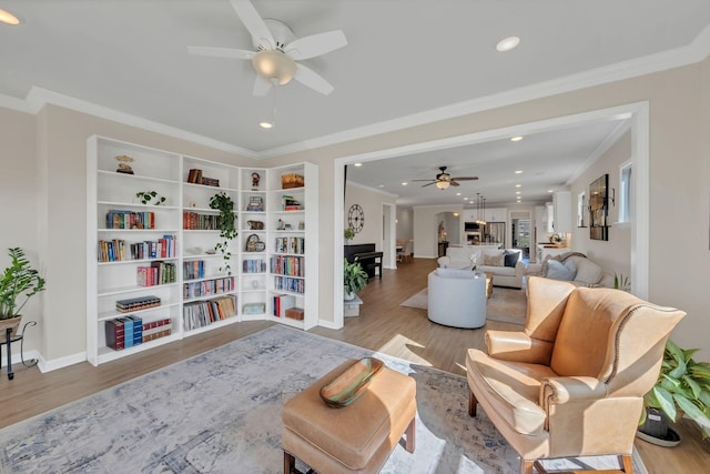 living area featuring a ceiling fan, baseboards, recessed lighting, wood finished floors, and ornamental molding