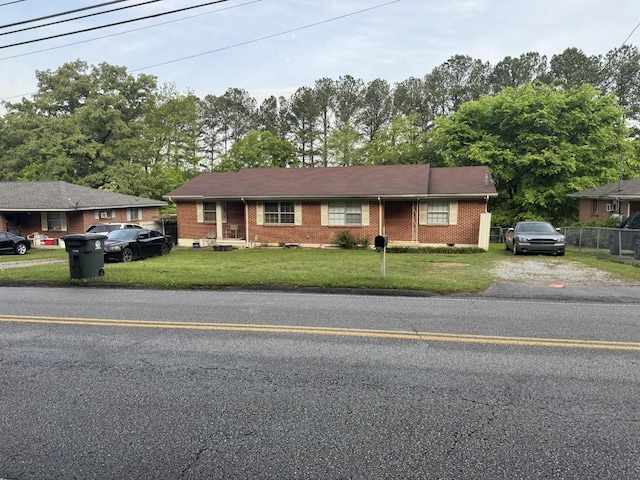 single story home featuring brick siding, fence, and a front lawn
