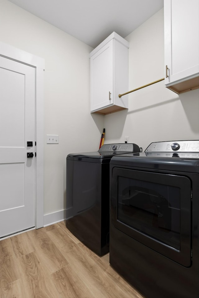 laundry area featuring cabinet space, baseboards, washing machine and dryer, and light wood finished floors