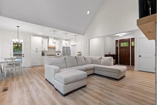 living area featuring an inviting chandelier, light wood finished floors, high vaulted ceiling, recessed lighting, and visible vents