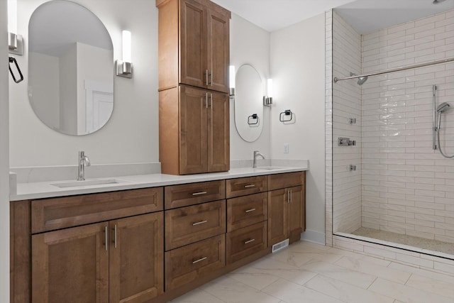 full bath featuring double vanity, a tile shower, a sink, and marble finish floor