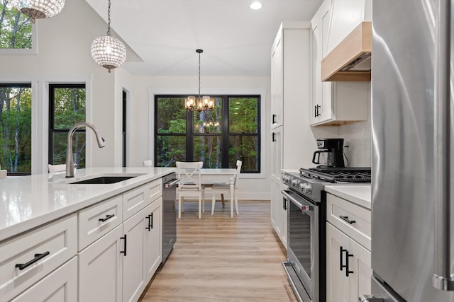 kitchen featuring an inviting chandelier, a sink, light countertops, premium range hood, and stainless steel appliances