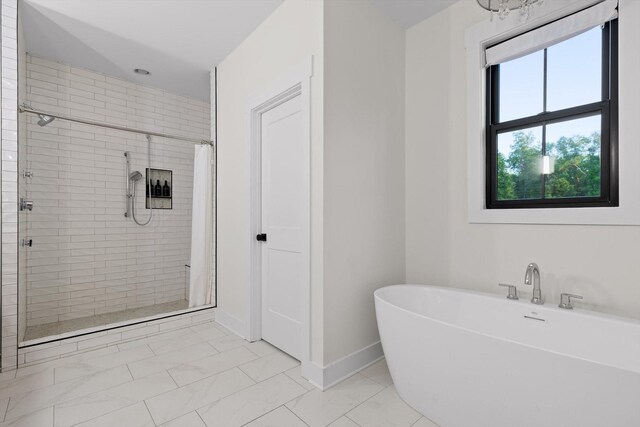 bathroom featuring baseboards, marble finish floor, a soaking tub, and a shower stall