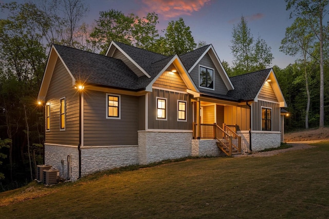 exterior space with a front lawn, covered porch, stone siding, a shingled roof, and board and batten siding
