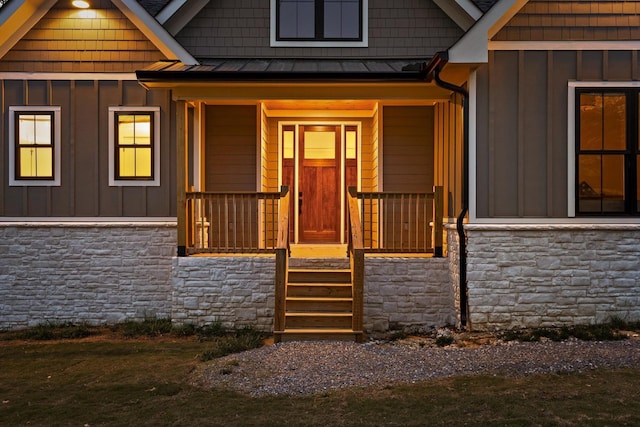 entrance to property with board and batten siding, a standing seam roof, and stone siding