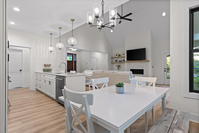 dining space featuring recessed lighting, high vaulted ceiling, light wood finished floors, and a fireplace