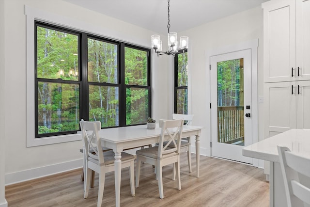 dining room featuring baseboards, light wood finished floors, and a notable chandelier