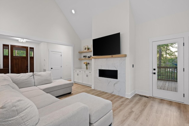 living room with high vaulted ceiling, baseboards, light wood-type flooring, and a premium fireplace