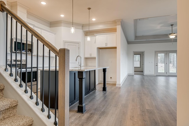 interior space featuring a ceiling fan, crown molding, wood finished floors, baseboards, and recessed lighting