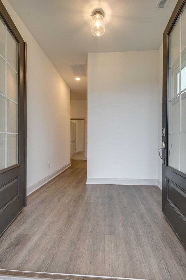 empty room with baseboards, wood finished floors, and visible vents