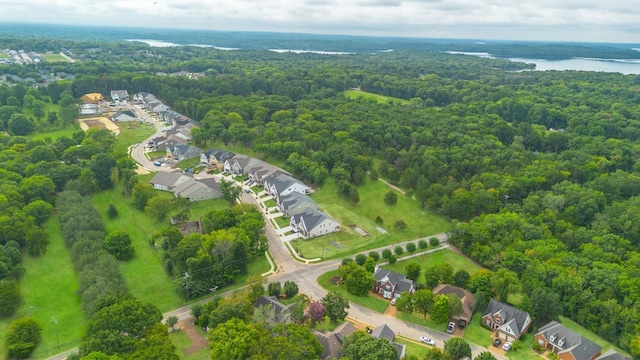 drone / aerial view featuring a water view, a residential view, and a wooded view