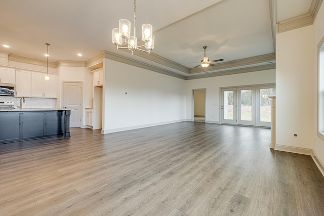 unfurnished living room featuring crown molding, light wood-style floors, baseboards, recessed lighting, and ceiling fan with notable chandelier