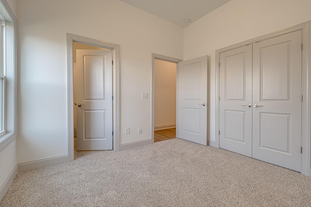 unfurnished bedroom with a closet, carpet, and baseboards