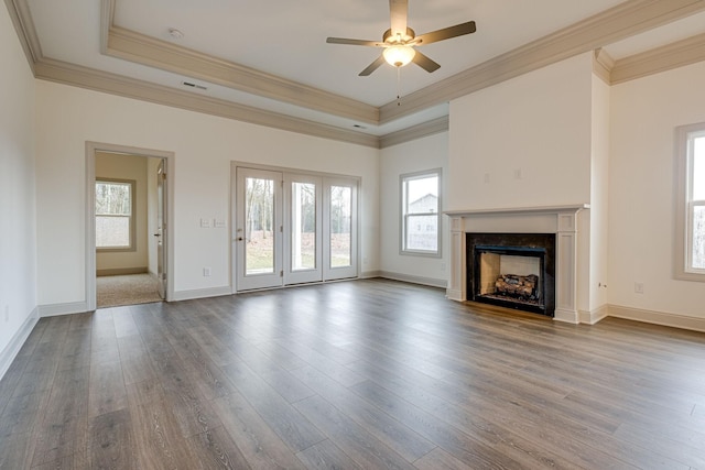 unfurnished living room featuring crown molding, a tray ceiling, and wood finished floors