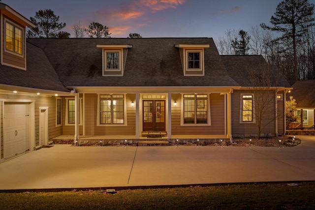 property entrance featuring covered porch, a shingled roof, concrete driveway, and french doors