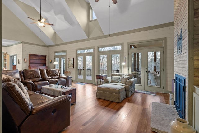 living area with ceiling fan, french doors, wood finished floors, high vaulted ceiling, and wooden walls