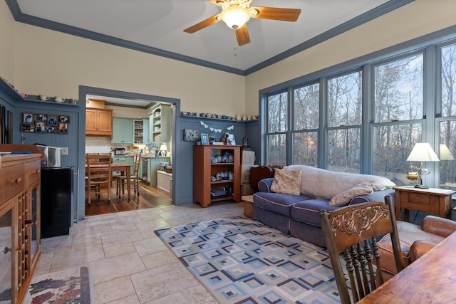 living room featuring stone tile floors, a ceiling fan, and ornamental molding