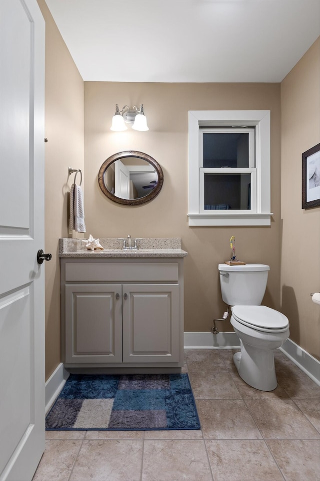 bathroom featuring baseboards, toilet, and vanity
