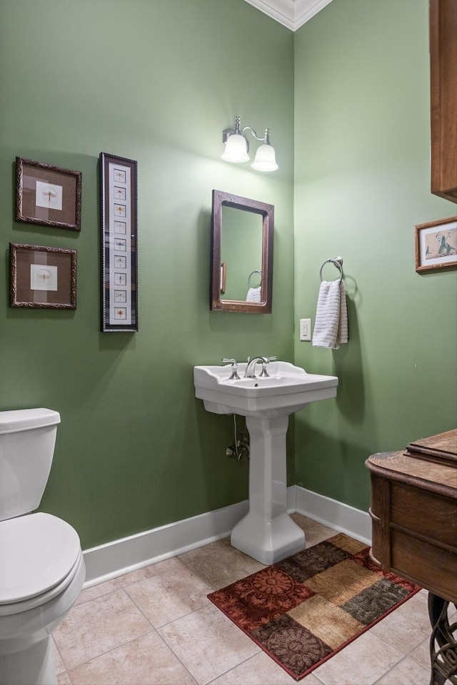 half bath with crown molding, toilet, baseboards, and tile patterned floors