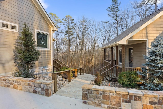 view of home's exterior featuring stairs and a shingled roof