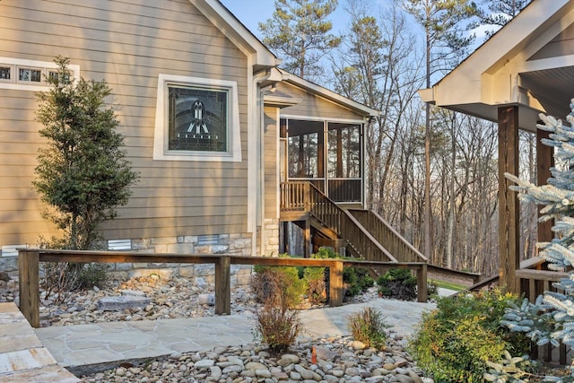 view of property exterior featuring a sunroom and stairway
