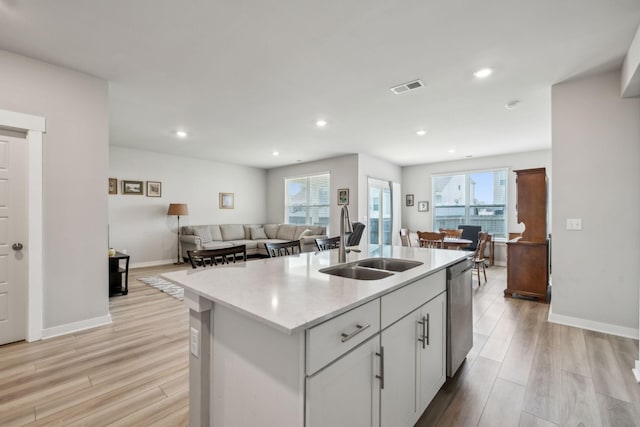 kitchen featuring a sink, dishwasher, light wood finished floors, and visible vents