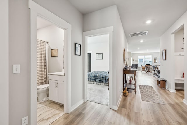 hallway with recessed lighting, baseboards, visible vents, and light wood-style flooring